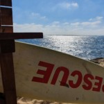 Une planche de surf "rescue" devant l'océan, connotant l'aide apportée par Christel Dijoux.