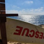 Une planche de surf "rescue" devant l'océan, connotant l'aide apportée par Christel Dijoux.